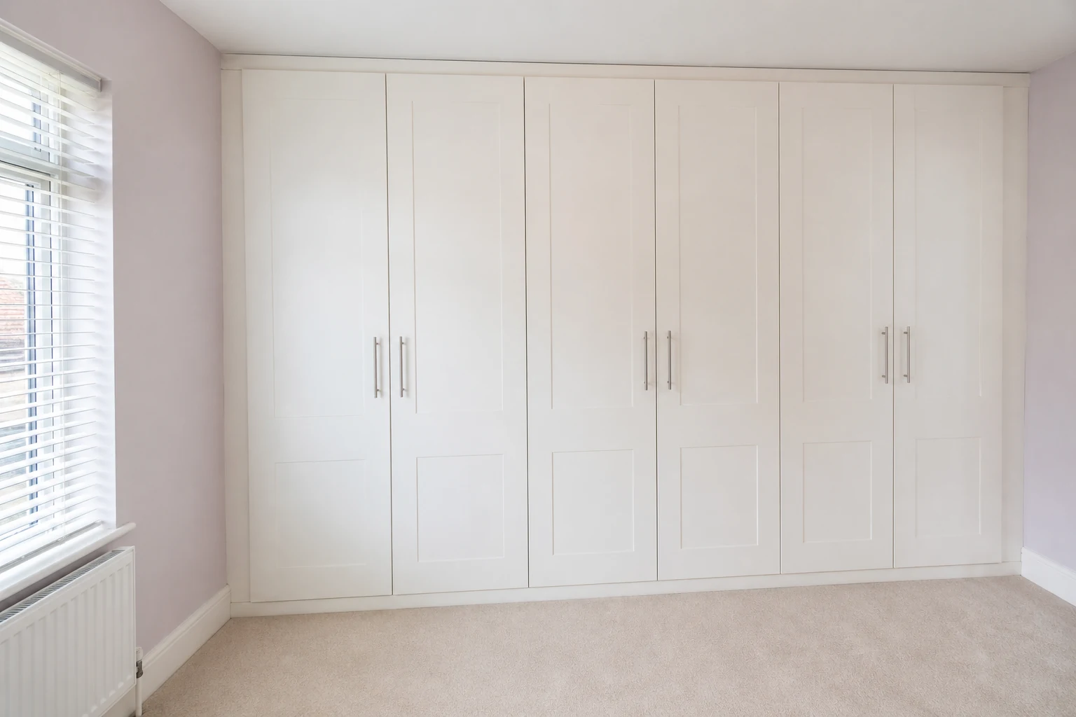 Floor-to-ceiling fitted wardrobes using a full bedroom wall