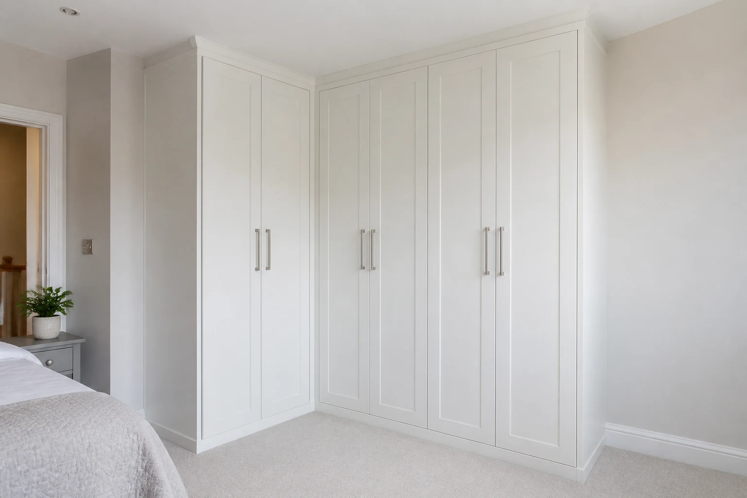 Light bedroom with white fitted wardrobe doors and soft pastel walls